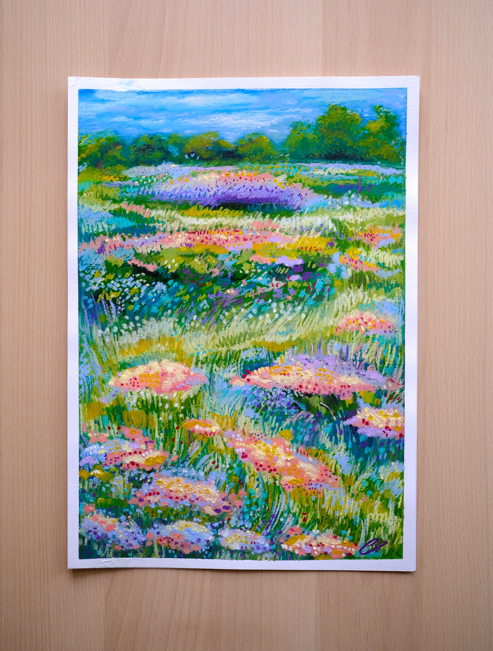Framed painting of a colorful floral landscape on a wooden table.