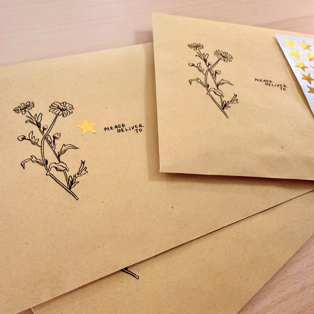 Kraft paper envelopes with floral designs and text on a wooden surface
